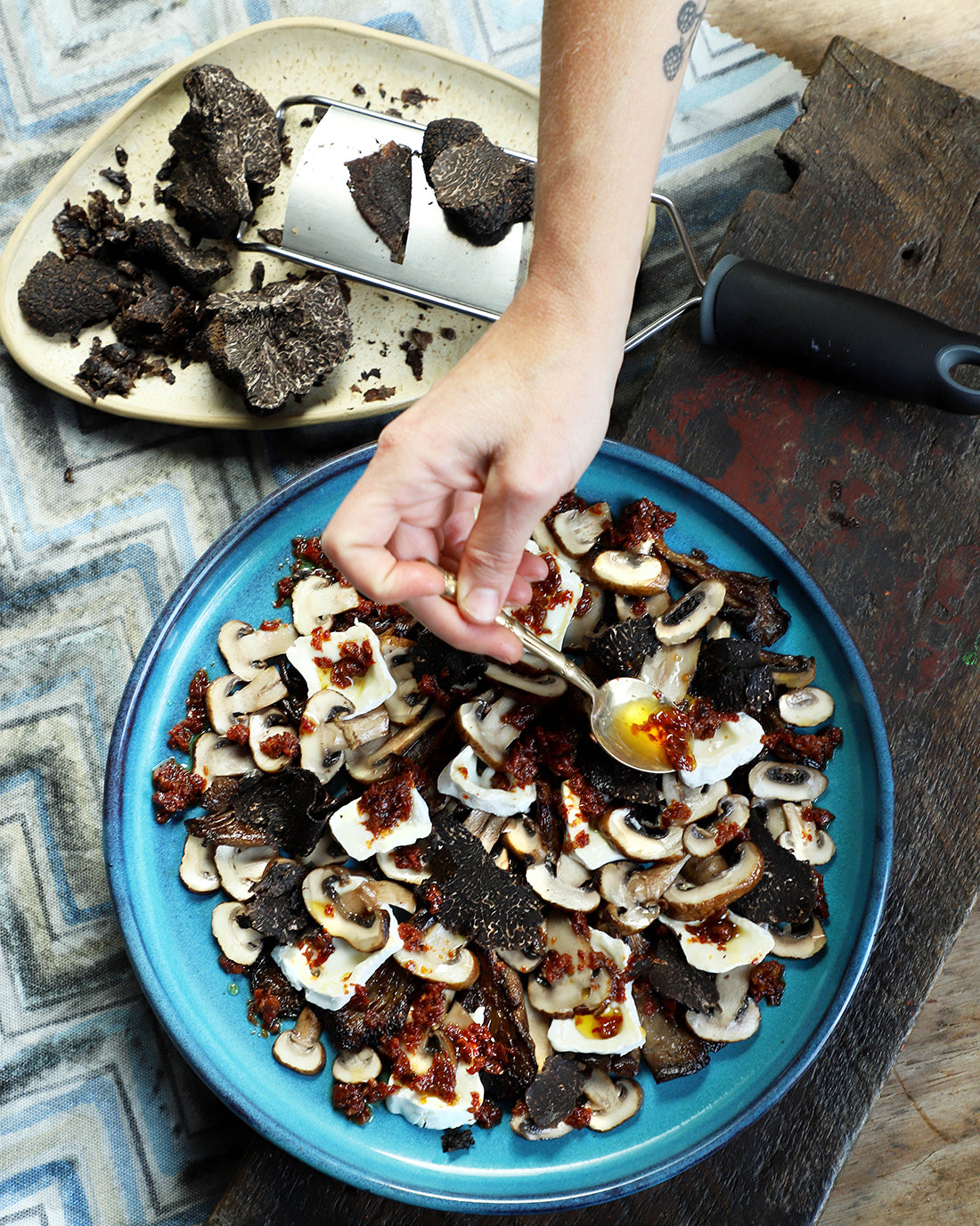 Carpaccio de hongos con brie, aliño de tomates secos y Trufa Negra