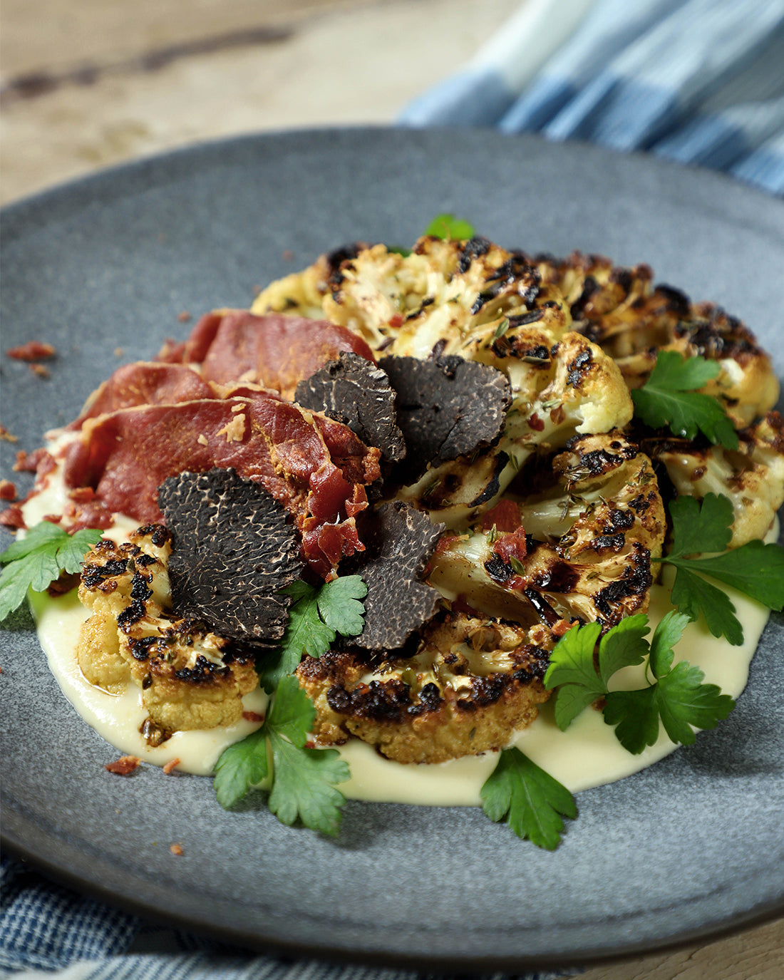 Bistec de coliflor marinada con crema de cabra, jamón crocante y Trufa Negra